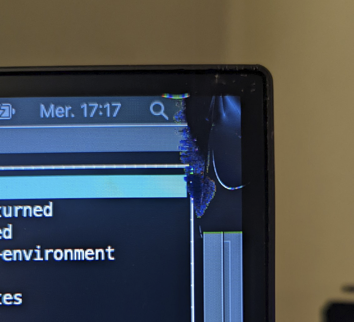 A computer monitor with the rightmost corner punctured, the panel is broken and dark